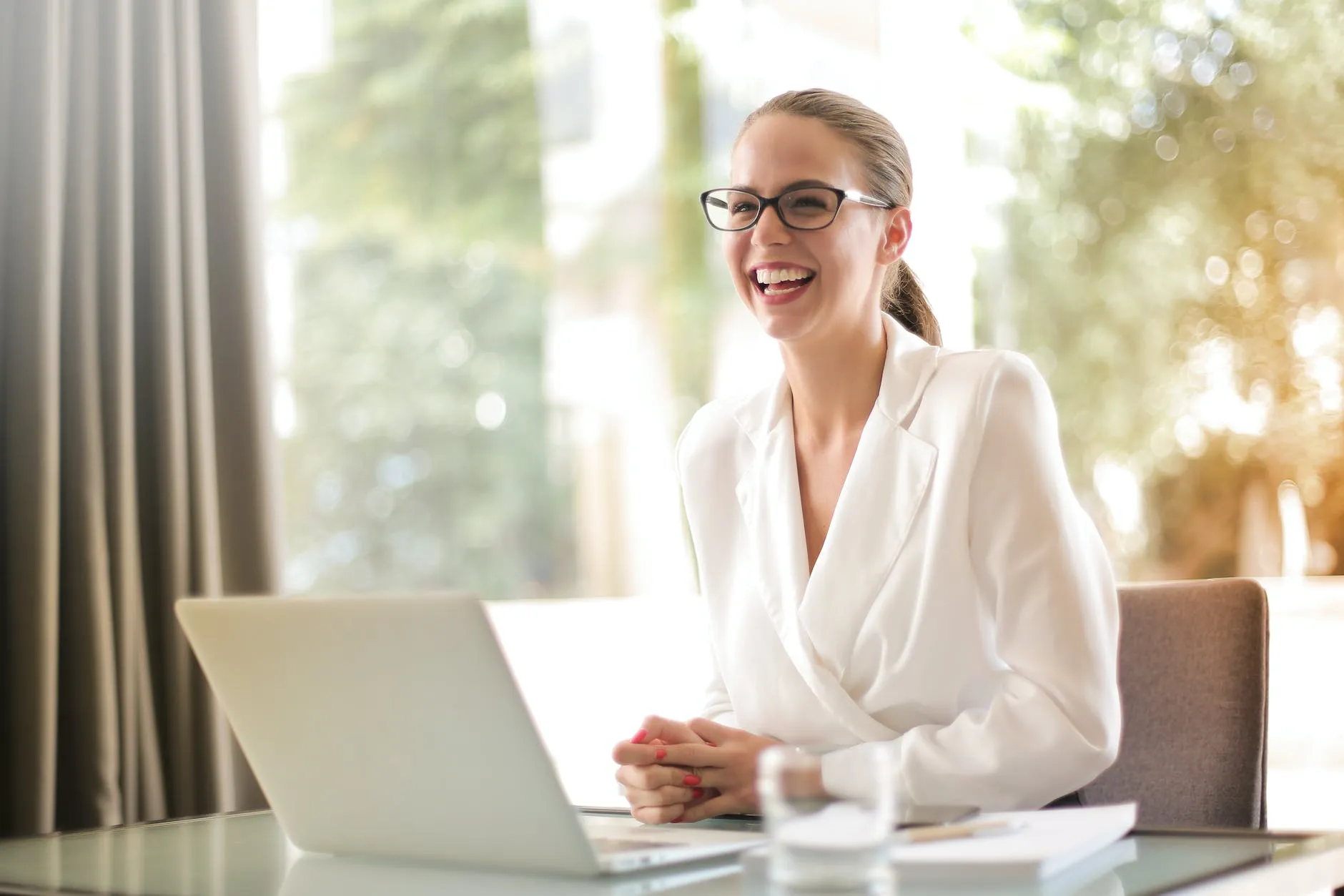 Femme d'affaires riante travaillant au bureau avec un ordinateur portable